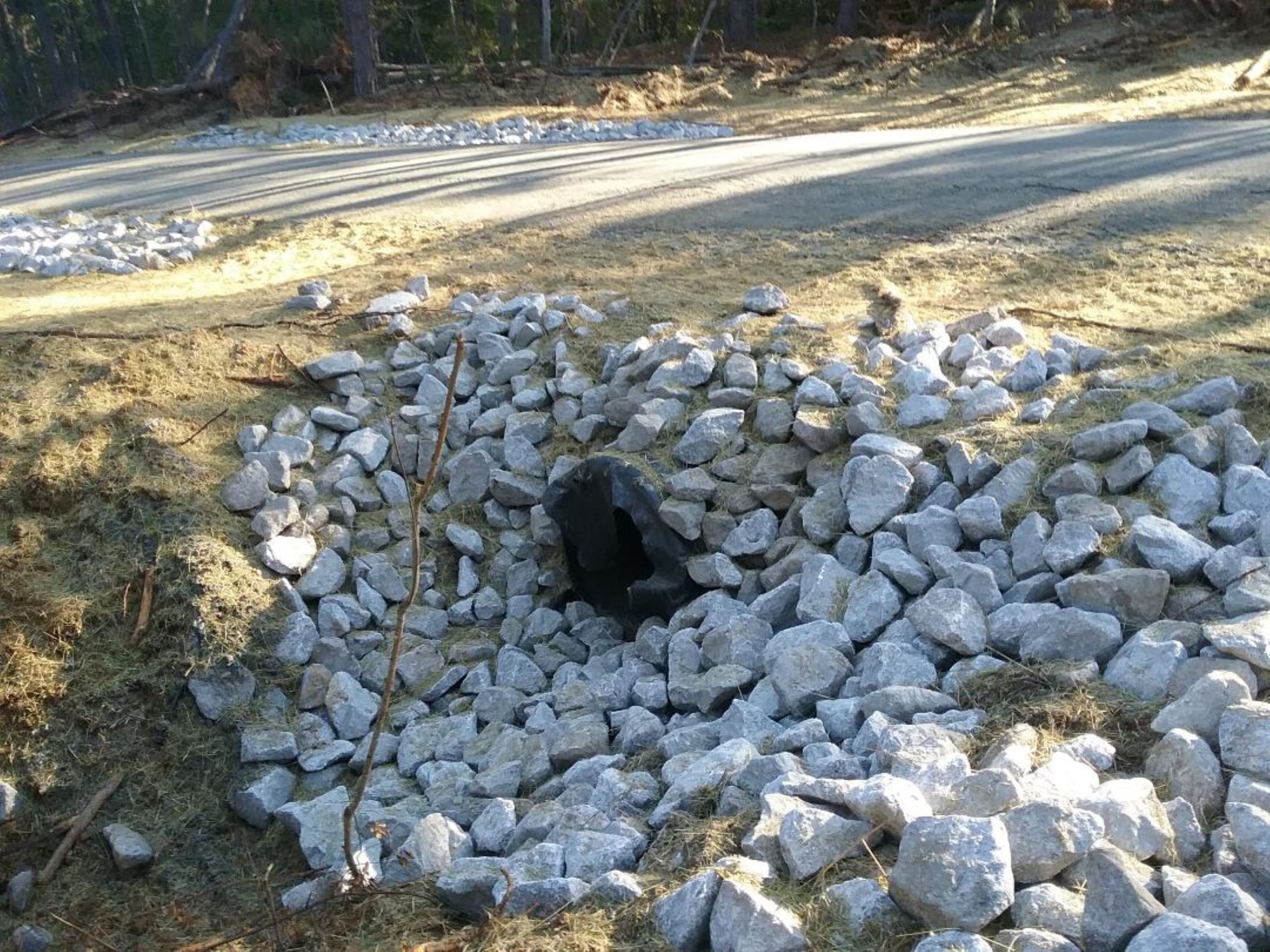 Culvert and surrounding stone alongside a completed road.